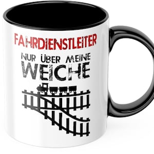 Könnte beinhalten: Weiße Keramik-Kaffeetasse mit schwarzem Henkel und Rand. Die Tasse hat eine schwarz-weiße Grafik einer Eisenbahnstrecke mit einem Zug darauf. Der Text "FAHRDIENSTLEITER NUR ÜBER MEINE WEICHE" ist in Schwarz und Rot auf die Tasse gedruckt.