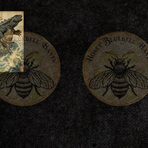 Puede incluir: Dos posavasos redondos con una ilustraci&oacute;n de abeja y el texto "HONEY BLUEBELL HAVEN" en un patr&oacute;n circular. Tambi&eacute;n hay una peque&ntilde;a impresi&oacute;n japonesa enmarcada que representa una criatura parecida a un lagarto en una ola.