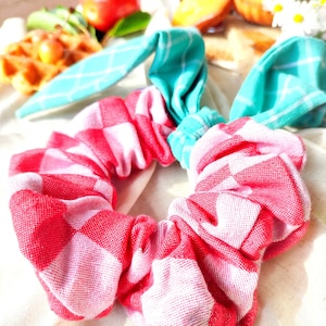 Può includere: Un elastico per capelli a scacchi rossi e bianchi con un fiocco a scacchi turchese e bianchi.