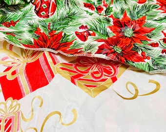 Op de afbeelding: Feestelijke kerststof met een poinsettia- en groenblijvend ontwerp. De bovenste laag toont rode poinsettia's, ornamenten en groene dennennaalden. De onderste laag heeft rode geschenkdozen met gouden linten op een witte achtergrond.