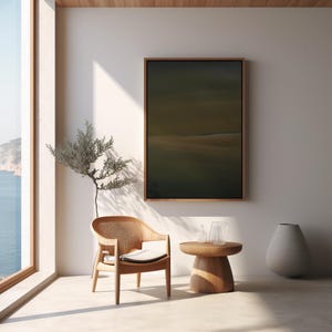 May include: A serene interior scene featuring a wooden armchair with a woven back and a small round side table. A framed abstract painting hangs on the wall. A tall, gray vase and a decorative plant add to the minimalist aesthetic. The room is bathed in natural light.