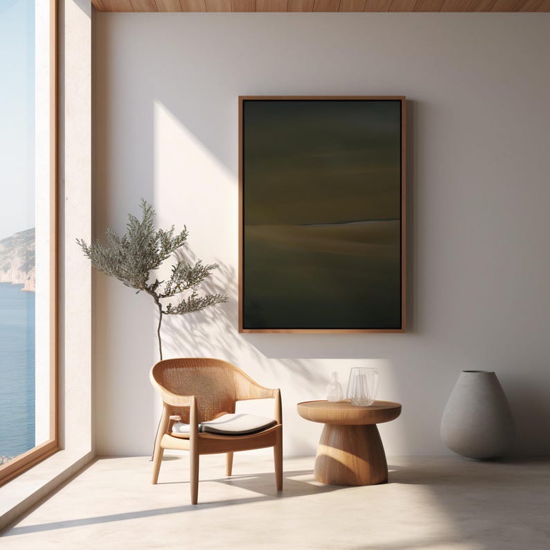 May include: A serene interior scene featuring a wooden armchair with a woven back and a small round side table. A framed abstract painting hangs on the wall. A tall, gray vase and a decorative plant add to the minimalist aesthetic. The room is bathed in natural light.