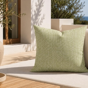 May include: A square throw cushion featuring a light green and white geometric pattern of small, repeating vertical rectangles. The cushion has a structured, plump appearance and is displayed on a neutral-coloured outdoor seating cushion.