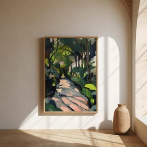 May include: A framed abstract painting of a sunlit path through a forest. The artwork features a palette of greens, pinks, and blues, with a wooden frame. The painting is displayed on a white wall, with a neutral-colored vase on the floor.