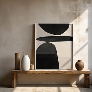 May include: A wooden bench displays a framed abstract art piece with black shapes on a cream background. Decorative vases in various sizes and materials, including a tall wooden vase, a white ceramic vase, and a small brown vase, are arranged on the bench.