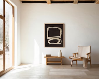May include: A square wall art piece featuring a black background with two stacked, hand-drawn style beige geometric shapes in a light wooden frame, displayed on a white wall above a wooden bench with a white vase and a small stack of books.
