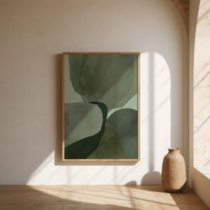 Op de afbeelding: Een rechthoekig wandkunstwerk met abstracte, overlappende organische vormen in diverse tinten salie-, olijf- en bosgroen, gevat in een eenvoudige, lichtgekleurde houten lijst die gecentreerd aan een neutrale muur is opgehangen.