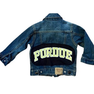 May include: A blue denim jacket with a black patch on the back that says "PURDUE" in yellow letters.