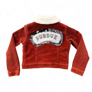 May include: A red corduroy jacket with a sherpa collar and a black and white bandana patch on the back that says "PURDUE".