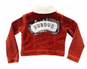 May include: A red corduroy jacket with a sherpa collar and a black and white bandana patch on the back that says "PURDUE".