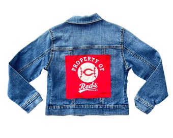 May include: A blue denim jacket with a red patch on the back that says "Property of Reds" with a baseball and a "C" inside a circle.