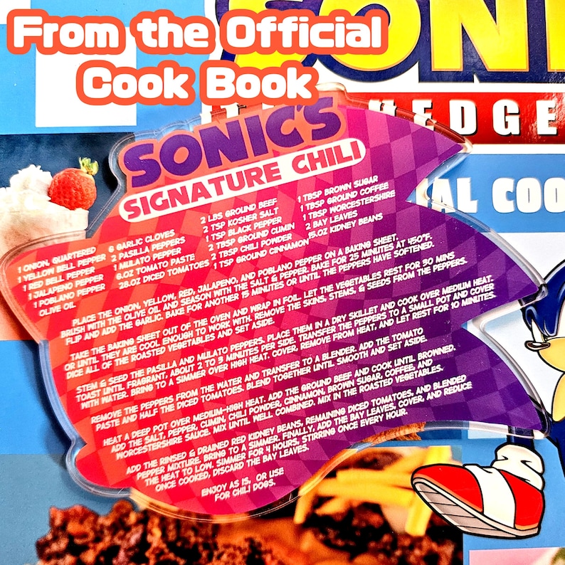 May include: A recipe card from the official Sonic the Hedgehog cookbook, featuring a recipe for Sonic's Signature Chili. The card has a purple and pink design with the Sonic logo and a picture of Sonic's shoe.