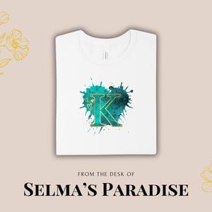 May include: White t-shirt with a teal blue watercolor design featuring the letter K in gold. The text "From the desk of Selma's Paradise" is printed below the design.