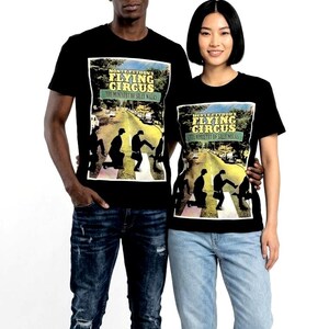 May include: Black t-shirts with a graphic from Monty Python's Flying Circus. The design shows a street scene with figures on a zebra crossing. The text "MONTY PYTHON'S FLYING CIRCUS" is above the image.