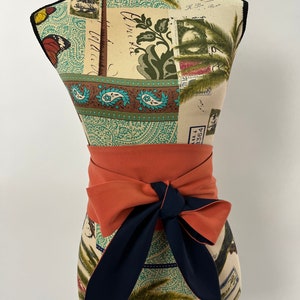 Könnte beinhalten: Ein rostiger Stoffgürtel mit einer dunkelblauen Schleife. Der Gürtel ist um eine Schaufensterpuppe mit einem gemusterten Stofftorso gebunden.