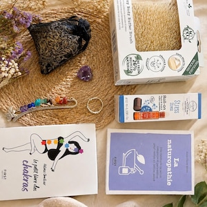 Peut inclure: Un ensemble d'articles de bien-être comprenant une brosse de massage corporel en boîte, un roll-on anti-stress, un petit sachet noir de lavande, une améthyste en forme de cœur, un marque-page en métal avec des pierres colorées et deux livres intitulés Le petit livre des chakras et La naturopathie.
