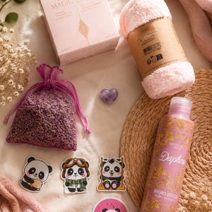 Puede incluir: Una colección de artículos que incluye una caja de Charlotte's Magic Cream, una diadema rosa difusa, una bolsa de organza morada con lavanda seca, una pequeña piedra morada en forma de corazón, cuatro pegatinas de panda y un gel de ducha Daphne.