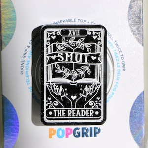 May include: Black and white tarot card phone grip with the text "XVII SMUT THE READER" on a white background.