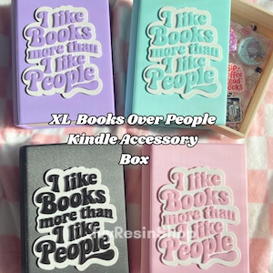 May include: Four Kindle accessory boxes in pastel colors: lavender, teal, gray, and pink. Each box features the text "I like Books more than I like People" in a retro font. The boxes are labeled "XL Books Over People Kindle Accessory Box."