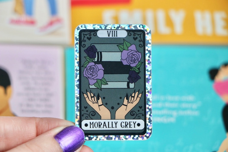 This listing features a "Morally Grey" tarot card design sticker, perfect for fans of romance books and tarot enthusiasts. The sticker showcases a tarot card illustration with intricate symbols and mystical details that represent the card's theme. The design captures a fantasy-inspired aesthetic, offering a glossy, vibrant finish. This high-quality sticker is ideal for decorating laptops, notebooks, water bottles, or any surface you want to personalize with a touch of bookish magic.