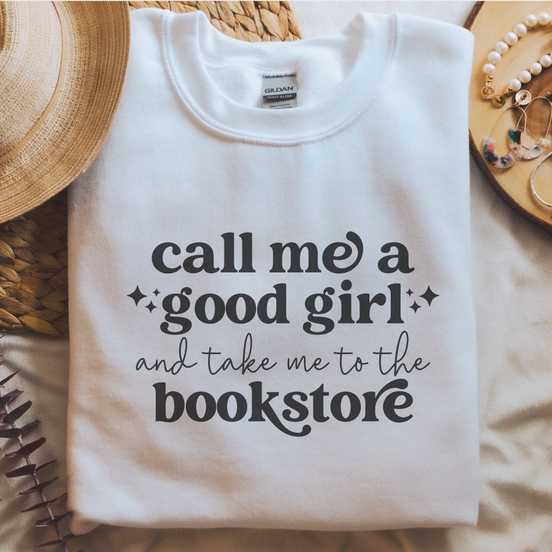 May include: White sweatshirt with black text that reads 'Call me a good girl and take me to the bookstore'.