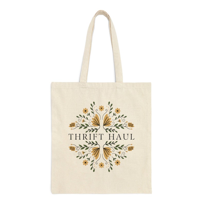Pu&ograve; includere: Una borsa tote beige con un design floreale e il testo "Thrift Haul" in nero.