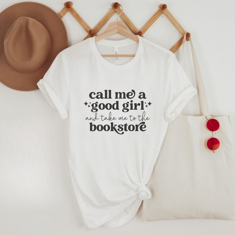 May include: White t-shirt with black text that reads "call me a *good girl* and take me to the bookstore".