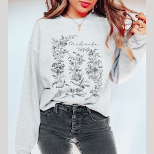 May include: Gray sweatshirt with a floral design and the word "Midwife" printed on the front.