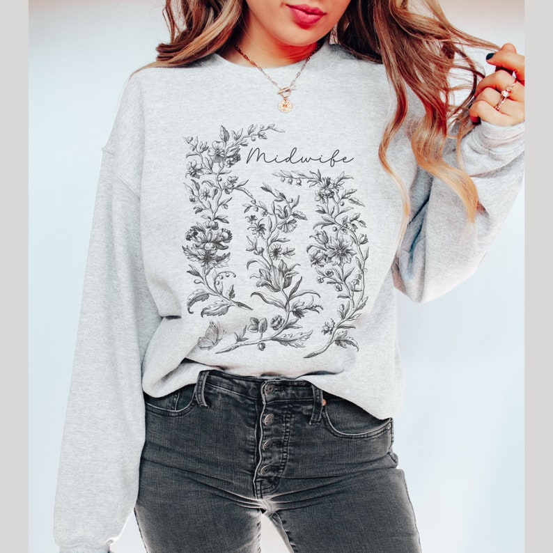 May include: Gray sweatshirt with a floral design and the word "Midwife" printed on the front.