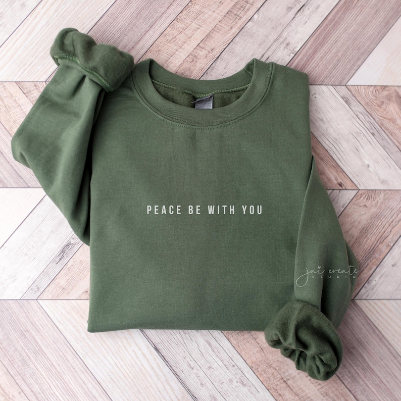 Pu&ograve; includere: Una felpa verde con la scritta "Peace be with you" stampata in bianco sul davanti.