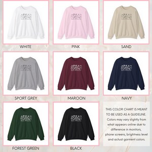 Pu&ograve; includere: Tabella colori che mostra dieci colori diversi di felpe con un design floreale e il testo "Two Warriors" stampato sul davanti. I colori sono bianco, rosa, sabbia, grigio sportivo, bordeaux, verde bosco, nero e blu navy.