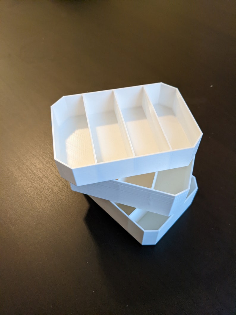 May include: Three white plastic trays stacked on top of each other. Each tray has four rectangular compartments.