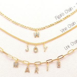 May include: Three gold chains with different styles and sizes. The top chain is a Figaro chain - 3mm, the middle chain is a Vine chain - 2.2mm, and the bottom chain is a Link chain - 4mm. Each chain has a charm with a letter on it.