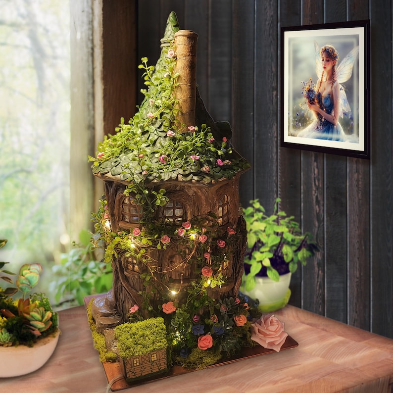May include: A brown, multi-story treehouse-style structure featuring a pointed roof covered in green vines and small pink flowers. The exterior is adorned with warm, glowing string lights, miniature windows, and a base decorated with moss and flowers.