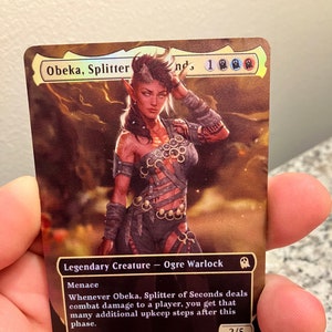May include: A fantasy trading card featuring Obeka, Splitter of Seconds, a red-skinned ogre warlock with horns and a menacing expression. The card has a black background with gold text and a 2/5 power and toughness rating. The card text reads: "Legendary Creature - Ogre Warlock. Menace. Whenever Obeka, Splitter of Seconds deals combat damage to a player, you get that many additional upkeep steps after this phase."