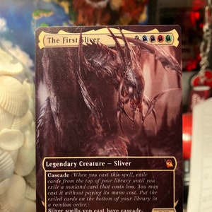 May include: A Magic: The Gathering card featuring The First Sliver, a legendary creature with a dark purple and black design. The card text reads "Cascade (When you cast this spell, exile cards from the top of your library until you exile a nonland card that costs less. You may cast it without paying its mana cost. Put the exiled cards on the bottom of your library in a random order.) Sliver spells you cast have cascade."
