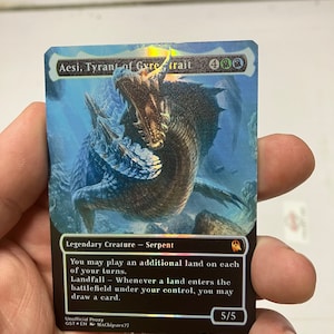 May include: Aesi, Tyrant of Gyre Trail, a black and blue Magic: The Gathering card featuring a large, green, and brown serpent with a blue background. The card text reads: "Legendary Creature - Serpent. You may play an additional land on each of your turns. Landfall - Whenever a land enters the battlefield under your control, you may draw a card. 5/5."