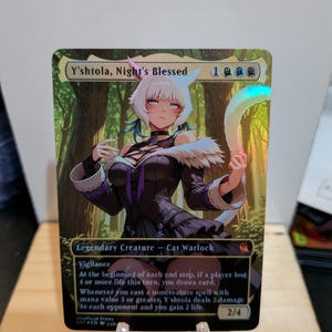 May include: A holographic trading card featuring an anime-style character named Y'shtola, Night's Blessed. The card displays the text 'Legendary Creature - Cat Warlock', a mana cost of 1, and a power/toughness of 2/4, set against a forest background.
