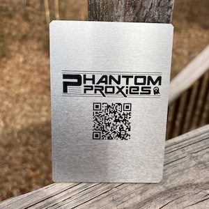 Puede incluir: Una tarjeta de metal plateada con el texto "PHANTOM PROXIES" y un c&oacute;digo QR en blanco y negro.