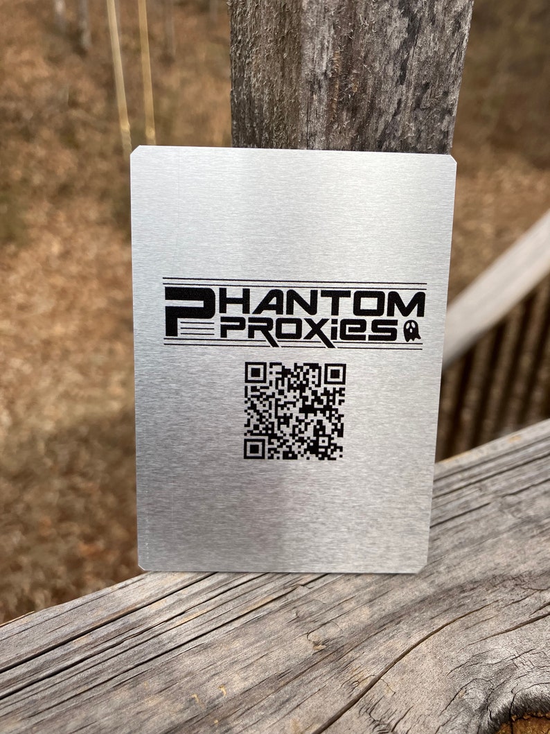 Puede incluir: Una tarjeta de metal plateada con el texto "PHANTOM PROXIES" y un c&oacute;digo QR en blanco y negro.
