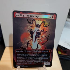 May include: A rectangular trading card titled Ashling, the Limitless, featuring a holographic finish. The card displays a dark, fiery illustration of a horned creature, with text detailing its abilities as a Legendary Creature - Elemental Sorcerer.
