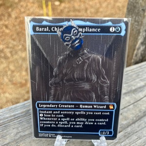 May include: A black and white Magic: The Gathering card with a blue and white illustration of a character with a mask. The card text reads "Baral, Chief of Compliance 1UU Legendary Creature - Human Wizard Instant and sorcery spells you cast cost less to cast. Whenever a spell or ability you control counters a spell, you may draw a card. If you do, discard a card. 1/3".