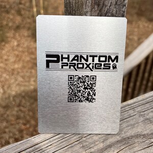 Puede incluir: Una tarjeta de metal plateada con el texto "PHANTOM PROXIES" y un c&oacute;digo QR en blanco y negro.