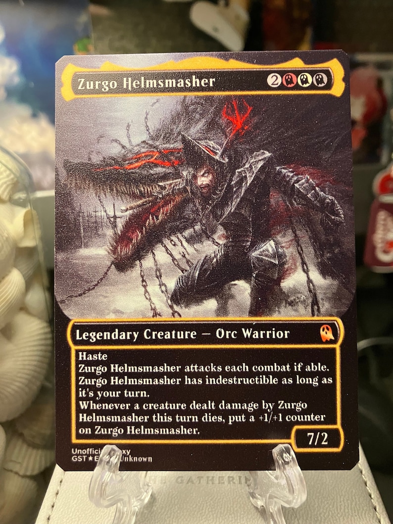 May include: A black and red illustrated card with the text "Zurgo Helmsmasher" and "Legendary Creature - Orc Warrior". The card has a black background with a red and white illustration of a creature with a helmet and chains. The card has a power of 7 and a toughness of 2.