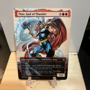 May include: A rectangular trading card titled Thor, God of Thunder featuring a comic-style illustration of a muscular figure with a hammer, a red cape, and blue armor. The card includes game text, a 5/5 power and toughness, and mana cost symbols.