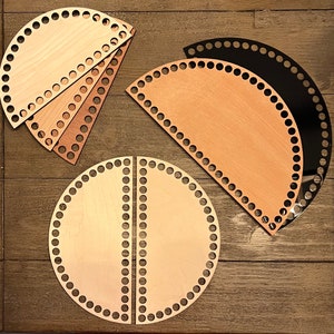 May include: Four wooden knitting loom shapes, two half-circle shapes and one full circle shape, all with holes around the edges. The half-circle shapes are in natural wood and the full circle shape is in two pieces.