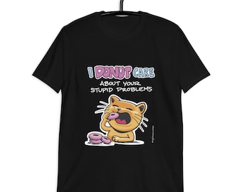 May include: Black t-shirt with the phrase "I DONUT CARE ABOUT YOUR STUPID PROBLEMS" in a playful font. A cartoon cat is eating a donut, with more donuts nearby. The shirt is hanging on a black hanger.