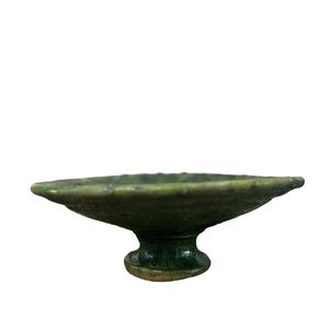 Peut inclure: Un bol en céramique vert sur pied avec un large bol peu profond et un pied rond et court.