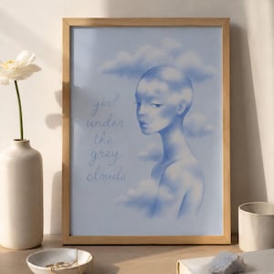 May include: A framed art print featuring a blue-toned illustration of a person with clouds. The text "girl under the grey clouds" is written in cursive. The artwork is in a light brown wooden frame.