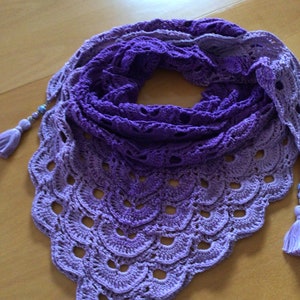 Könnte beinhalten: Ein handgehäkeltes Tuch in Lilatönen, das von hellem Lavendel zu tiefem Violett übergeht. Das Tuch hat einen gewellten Rand mit kreisförmigen Öffnungen und ist mit Quasten und Perlen verziert.